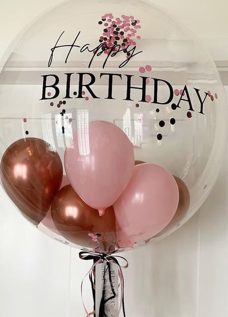A clear, transparent birthday bubble balloon , tied with a colorful ribbon.
